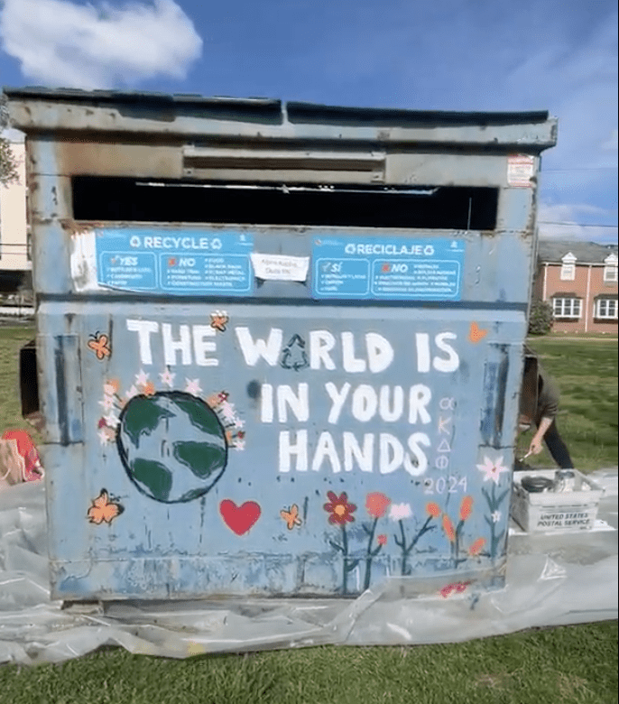 Dumpster painted with "The World is In Your Hands"