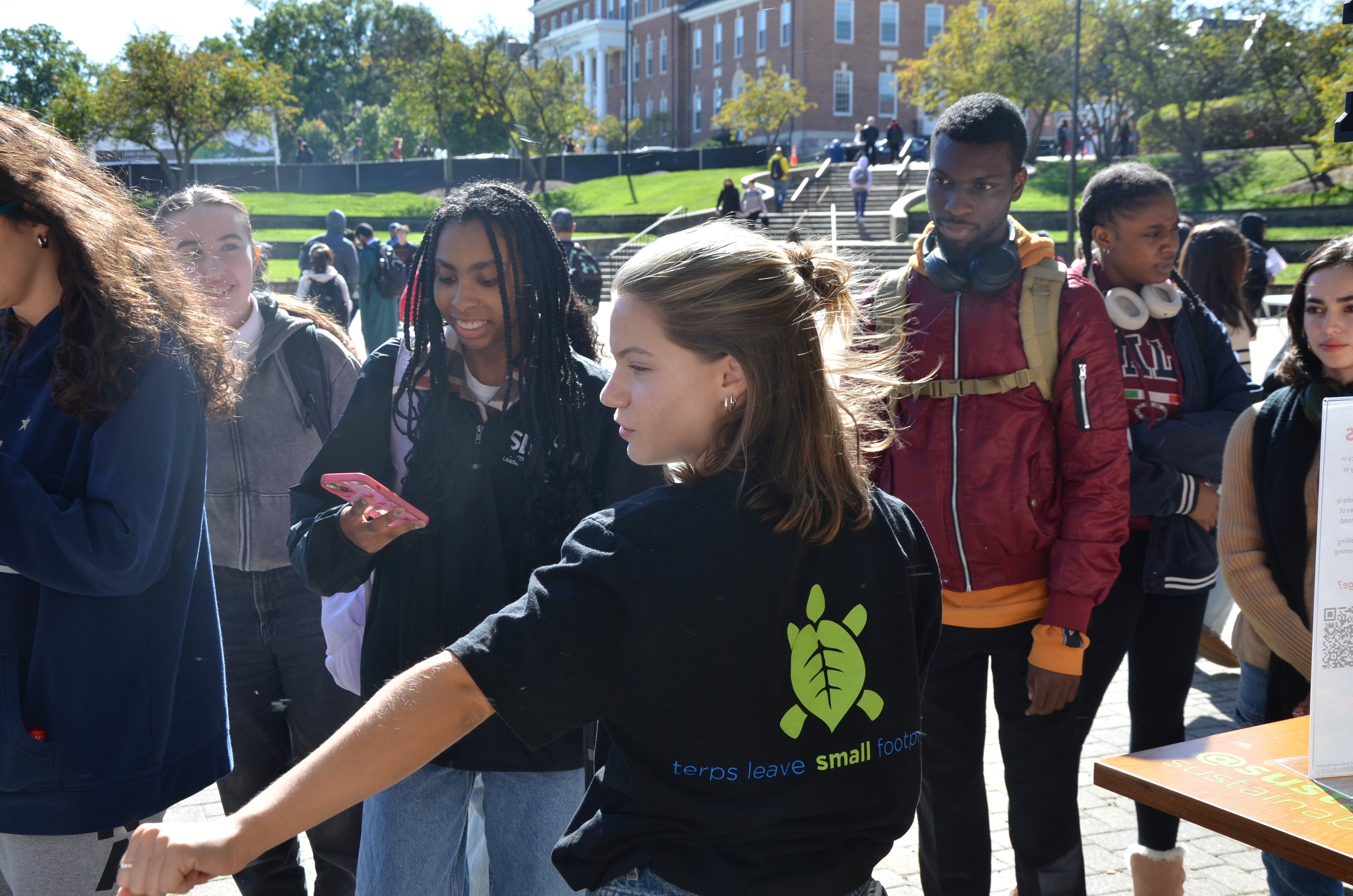 Student in turtle shirt talking with other students