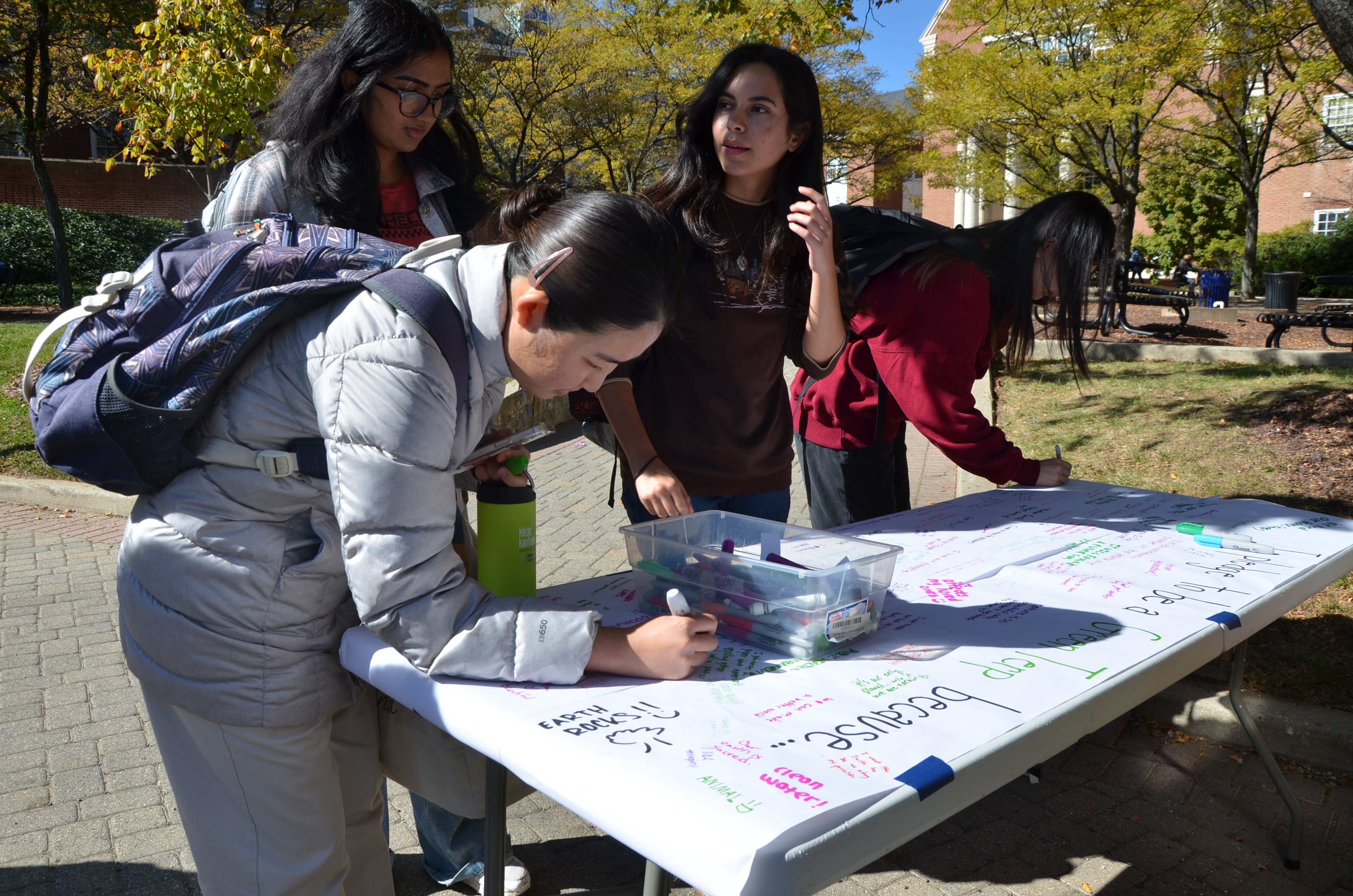 Students writing on white paper on table