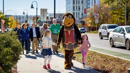 Parade down street including testudo mascot and kids.