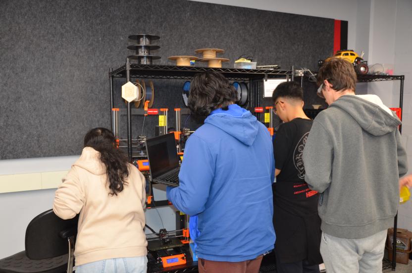 Engineering students huddle around a computer