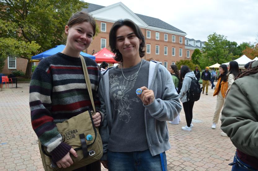 Two students holding up the buttons they created