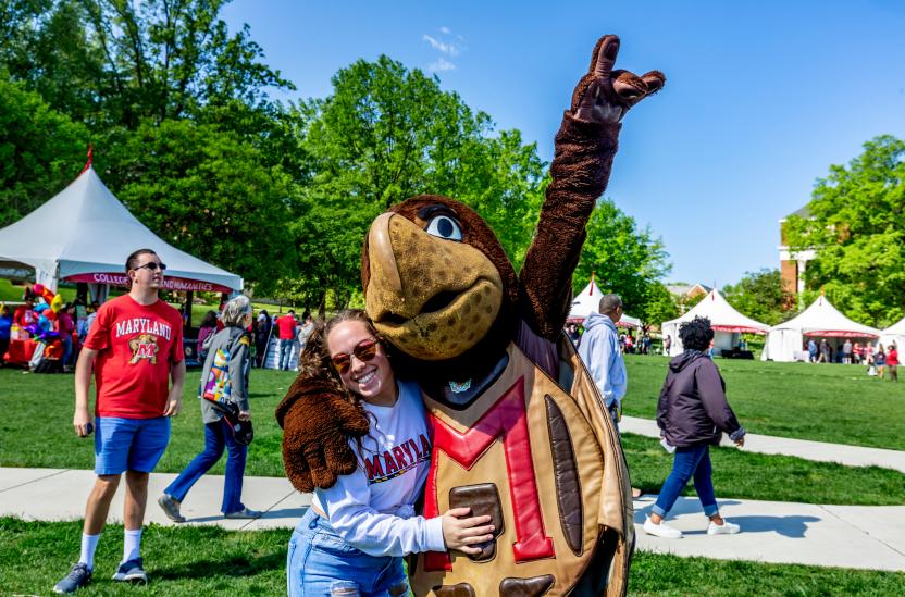 Testudo and woman in Maryland sweatshirt on Maryland Day 2019. Photo by Stephanie S. Cordle.