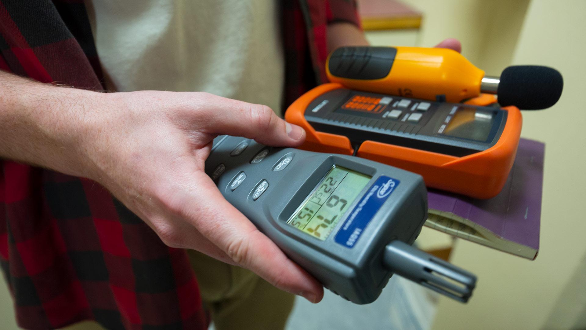 UMD student holding equipment used to study energy efficiency in campus buildings