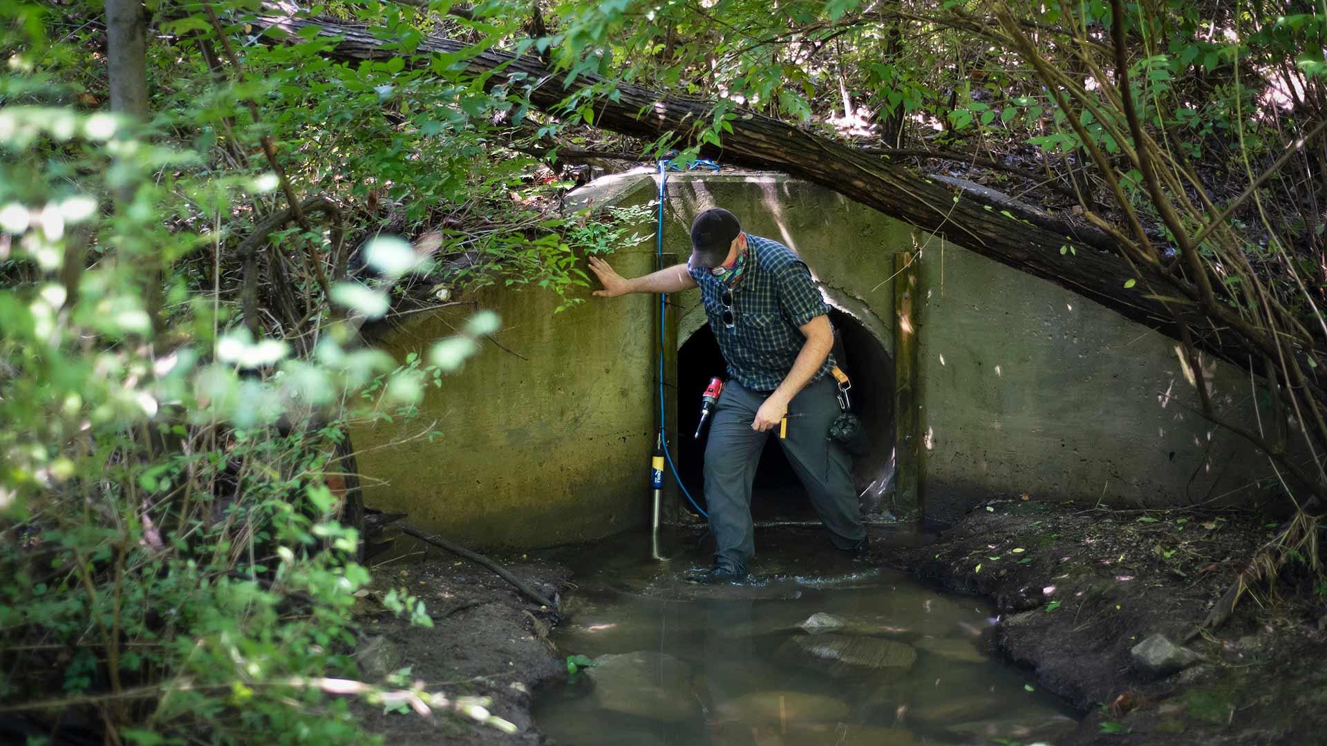 UMD staff applying storm sensor to on-campus stormwater drain