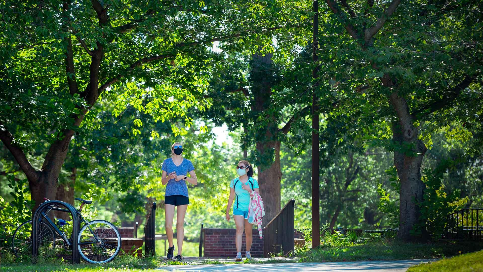 Students walking along campus pathway during the summer