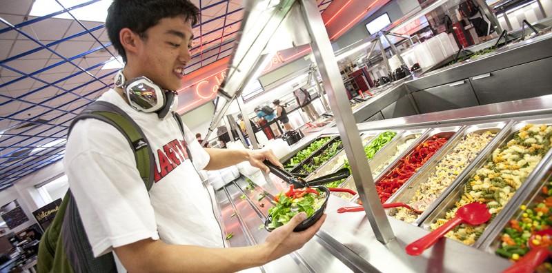 Student serves himself food in Dining Hall (pre COVID)