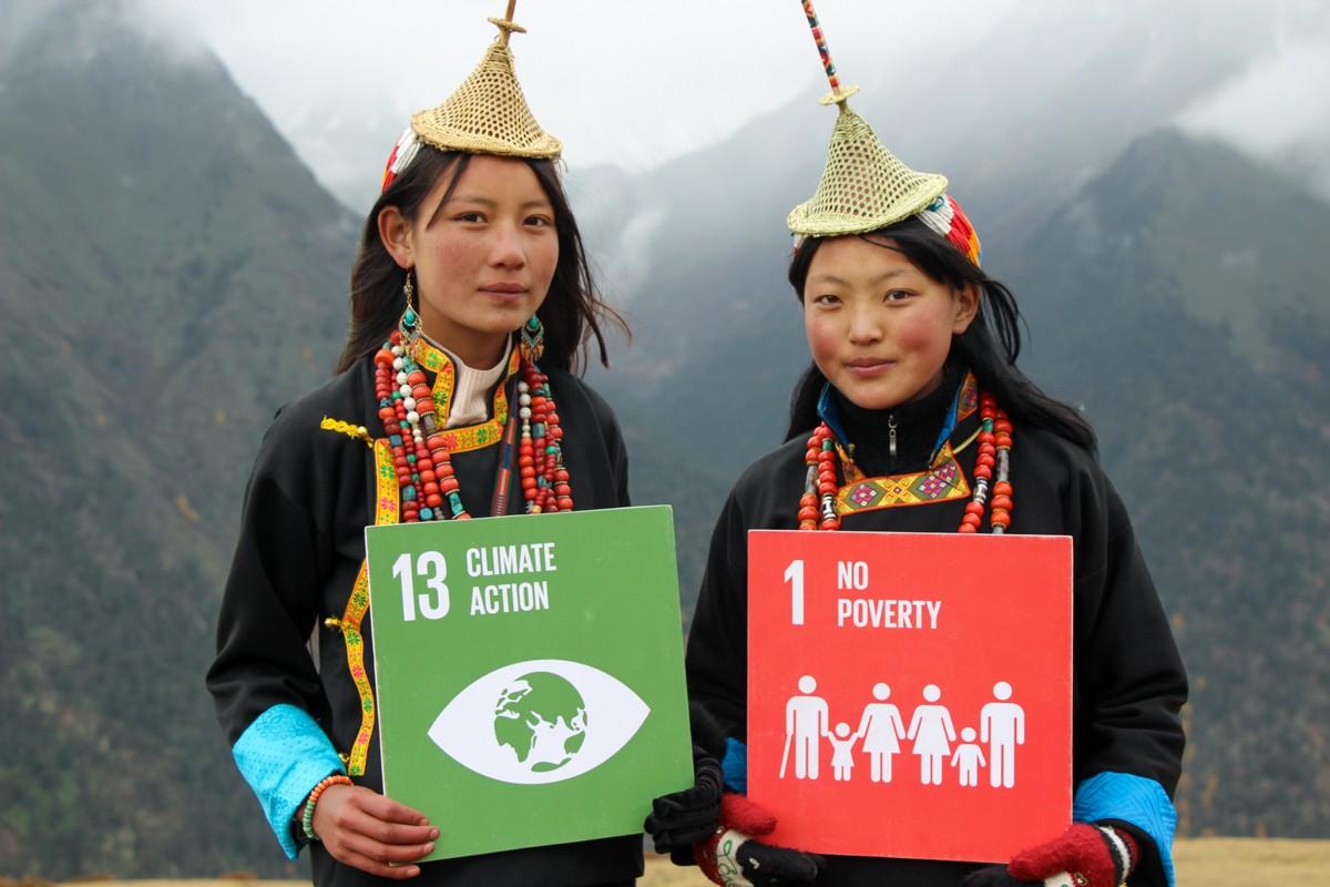 Photo of two teenage Bhutanese girls with signs for Climate Action (13) and No Poverty (1) Sustainable Development Goals (photo credited to: UNDP Bhutan).