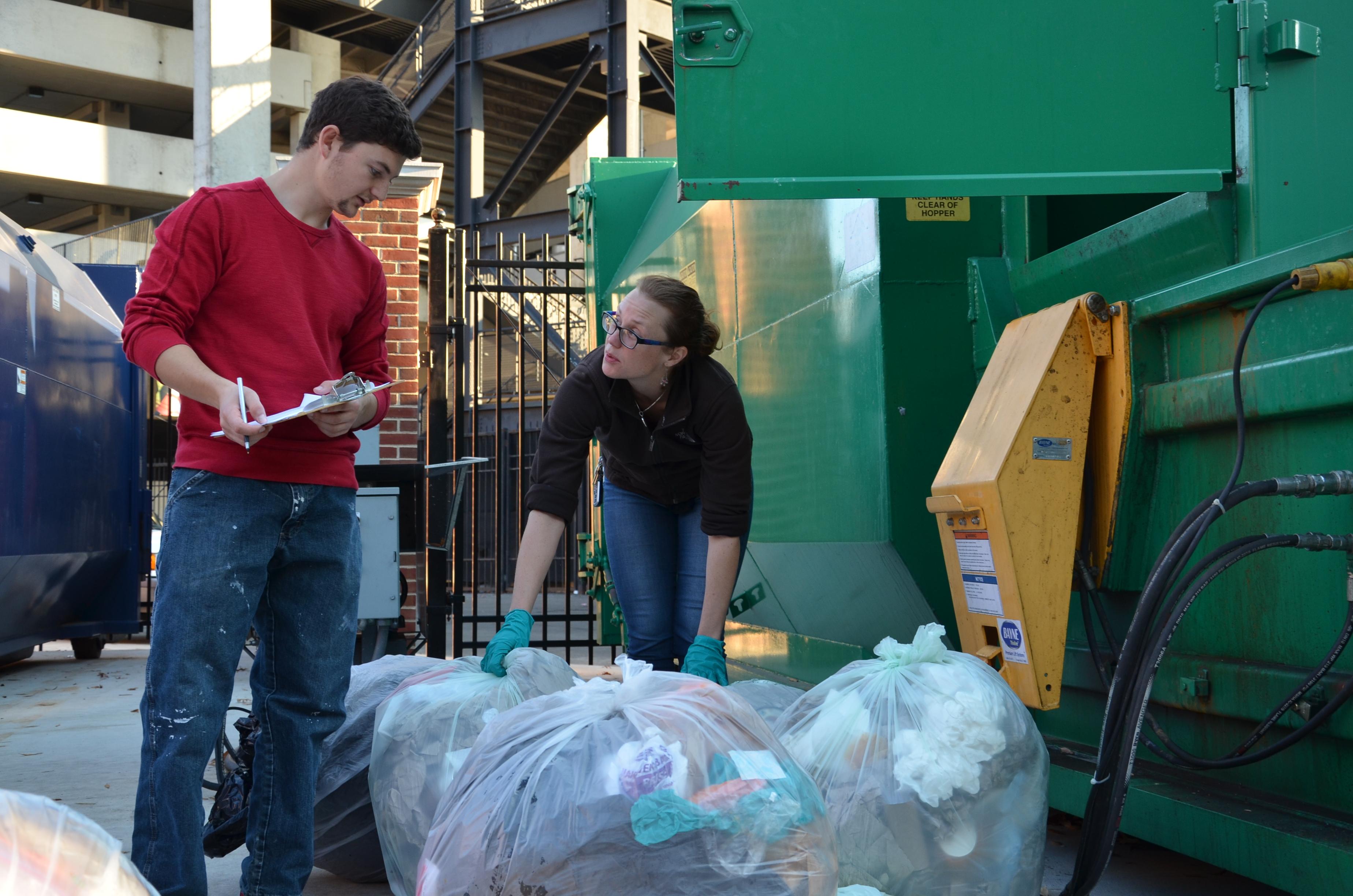 Recycling Coordinator and student move waste into dumpster