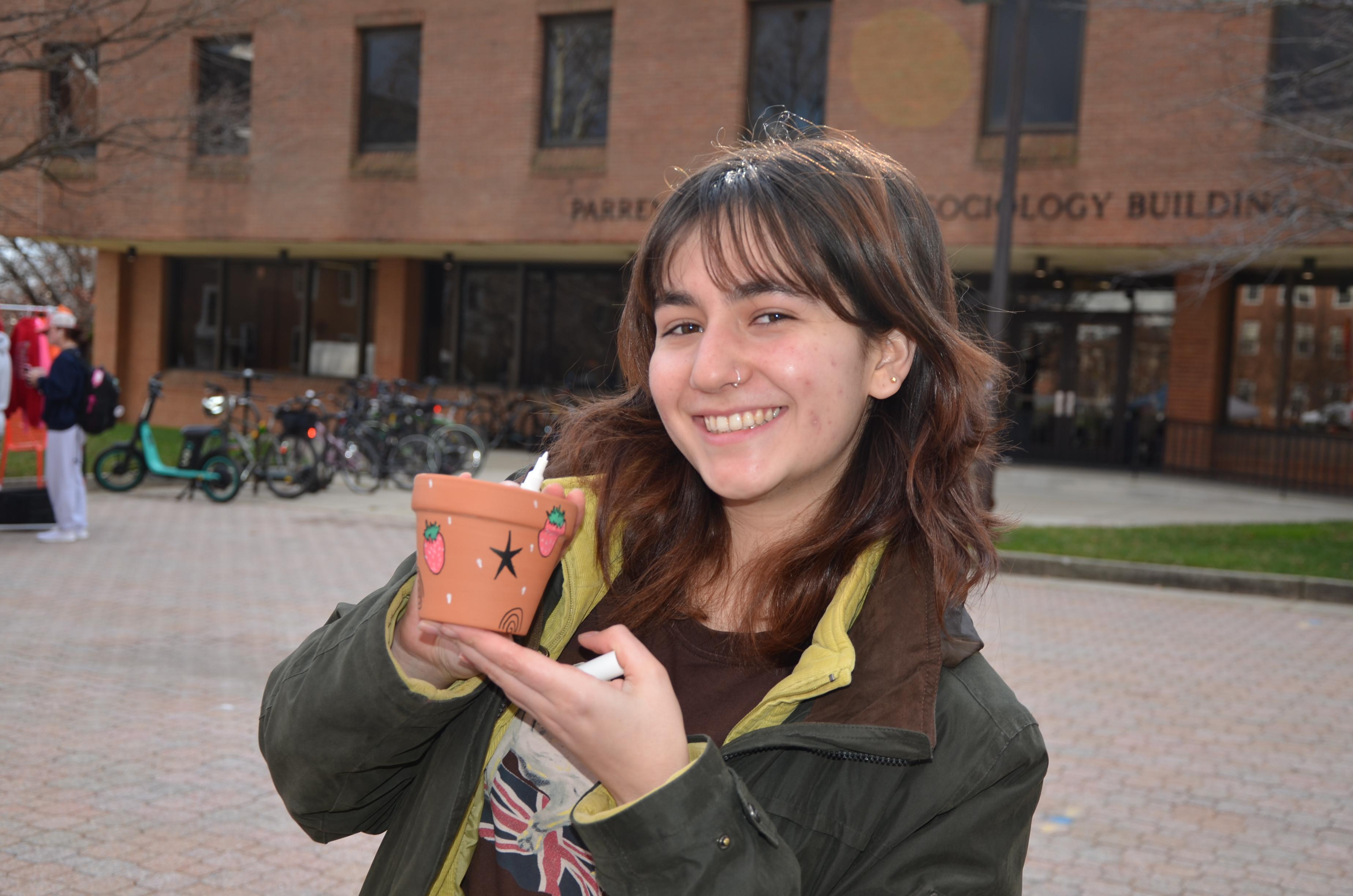 student posing with a pot they decorated that has strawberries and stars on it