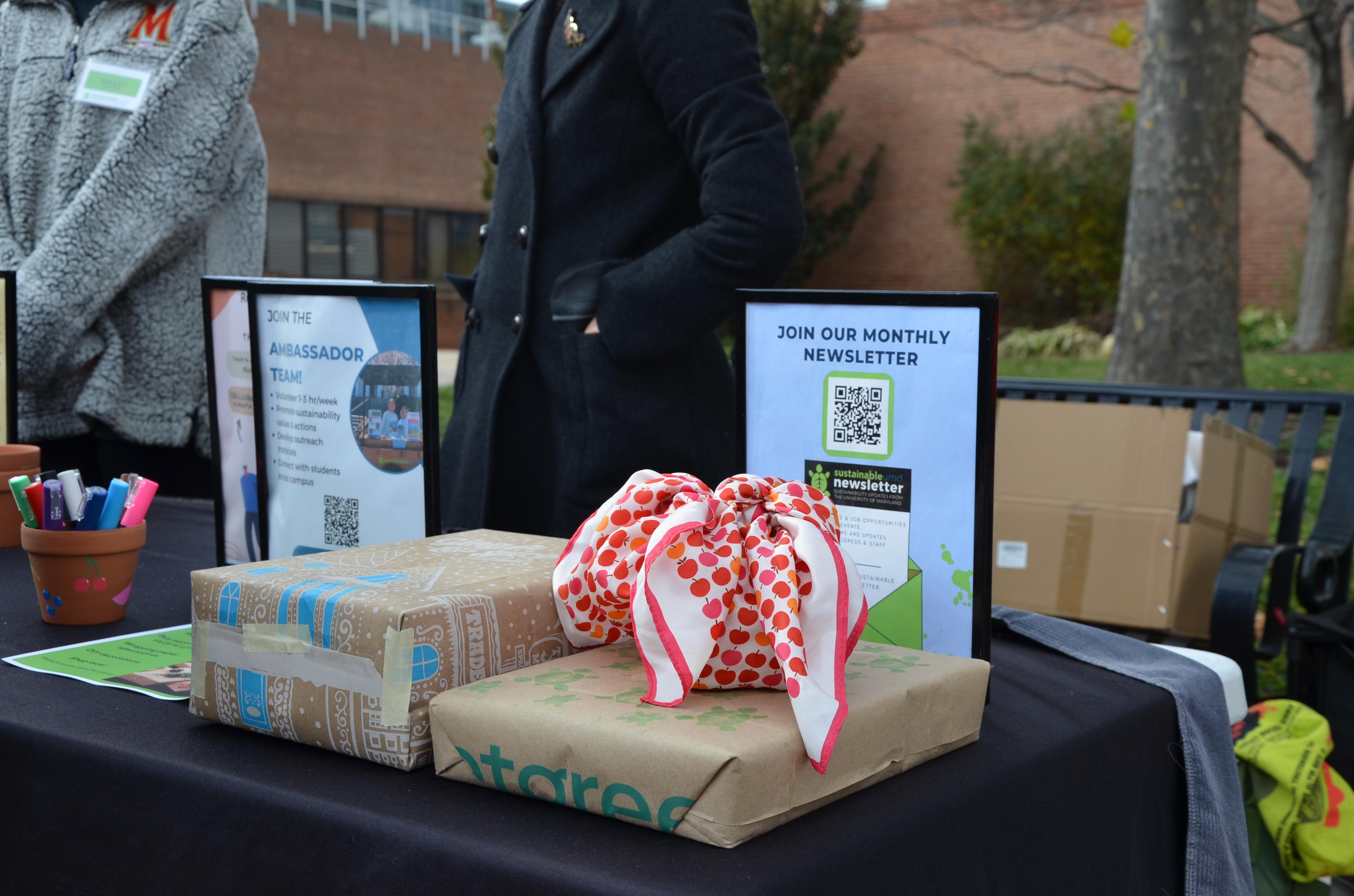 sustainable gift wrapping options at the holiday market such as scarves, kraft paper, and paper bags.
