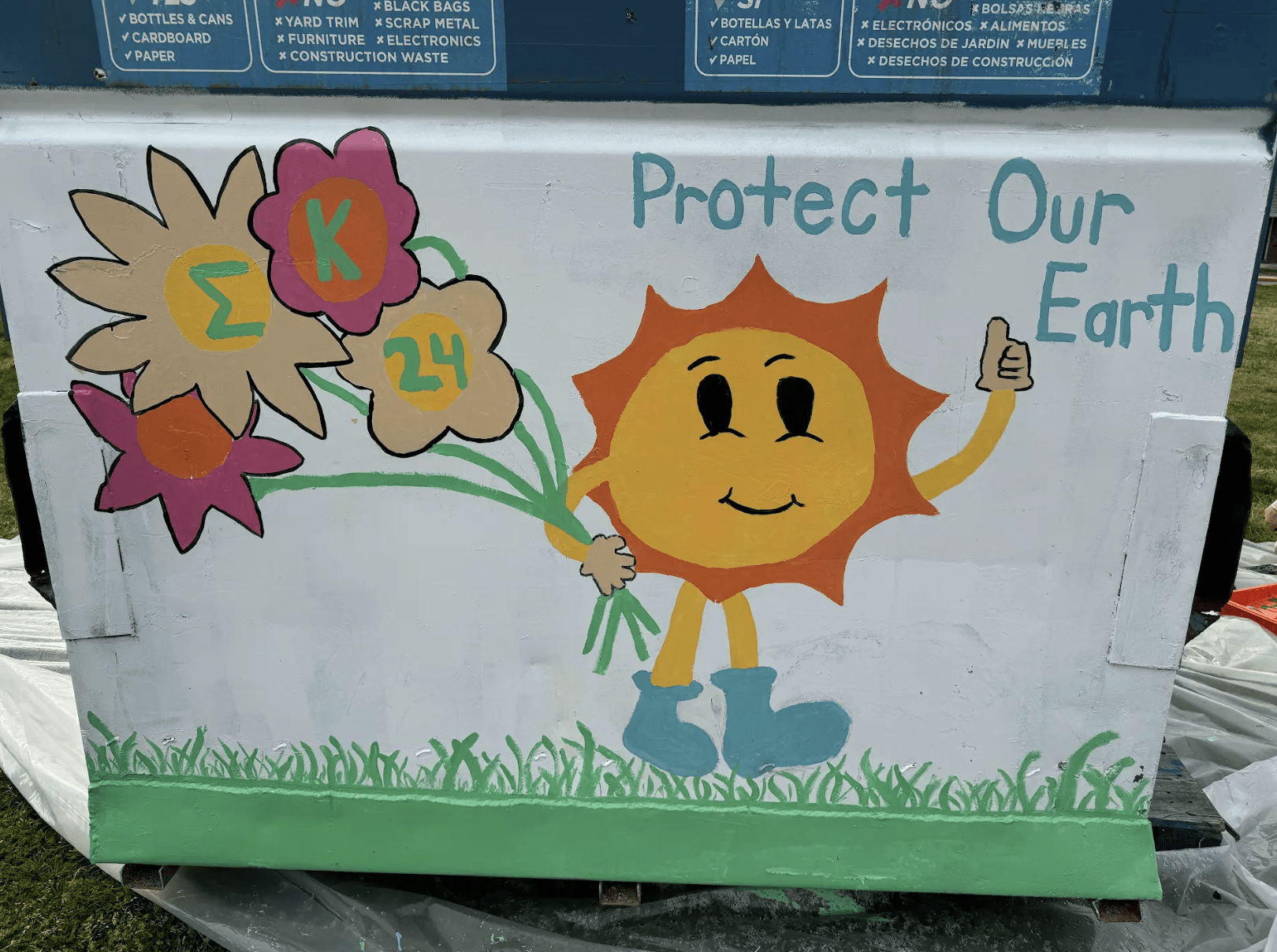 Dumpster painted with "Protect our Earth", sun holding flowers