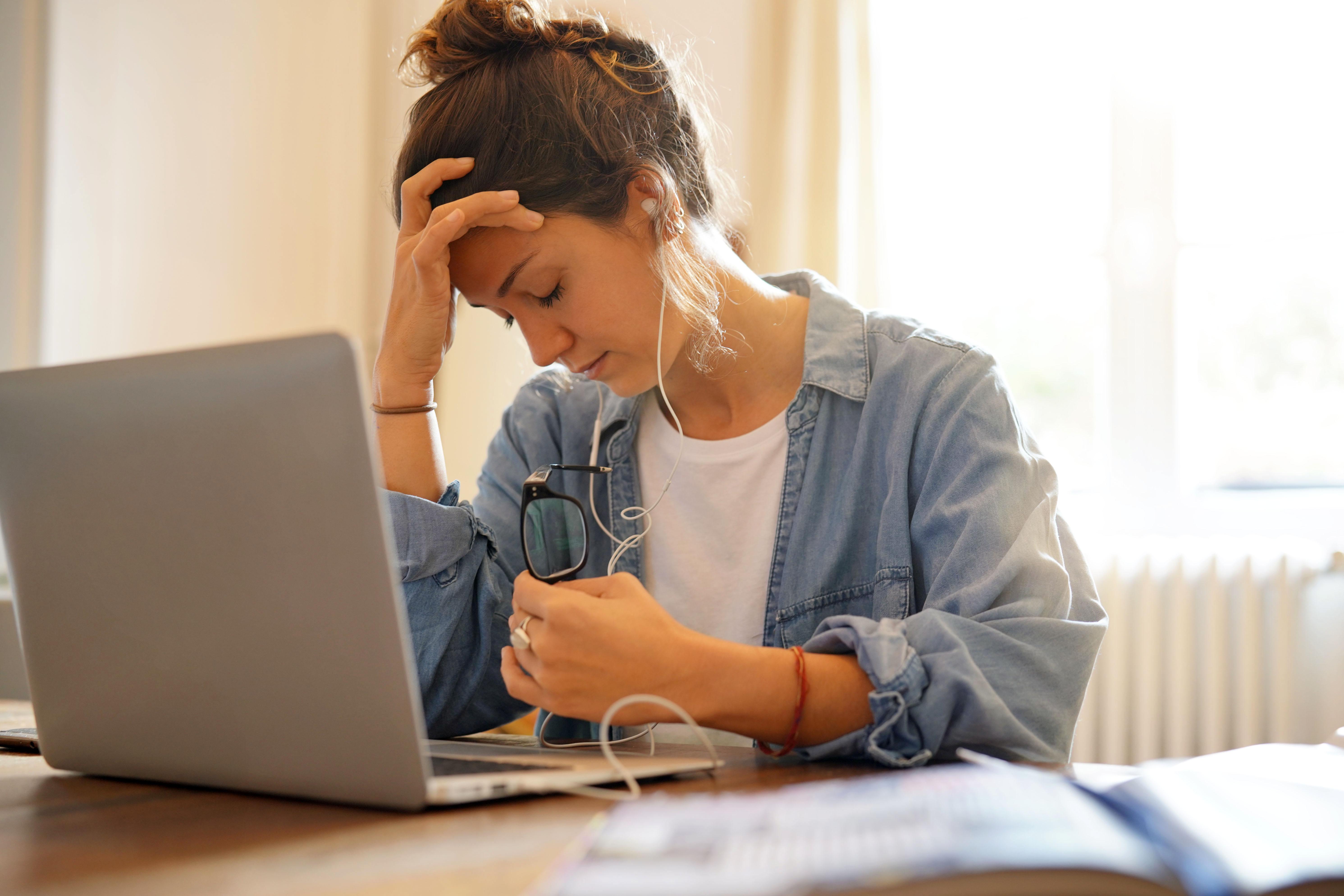 Young woman at laptop with head resting in hand