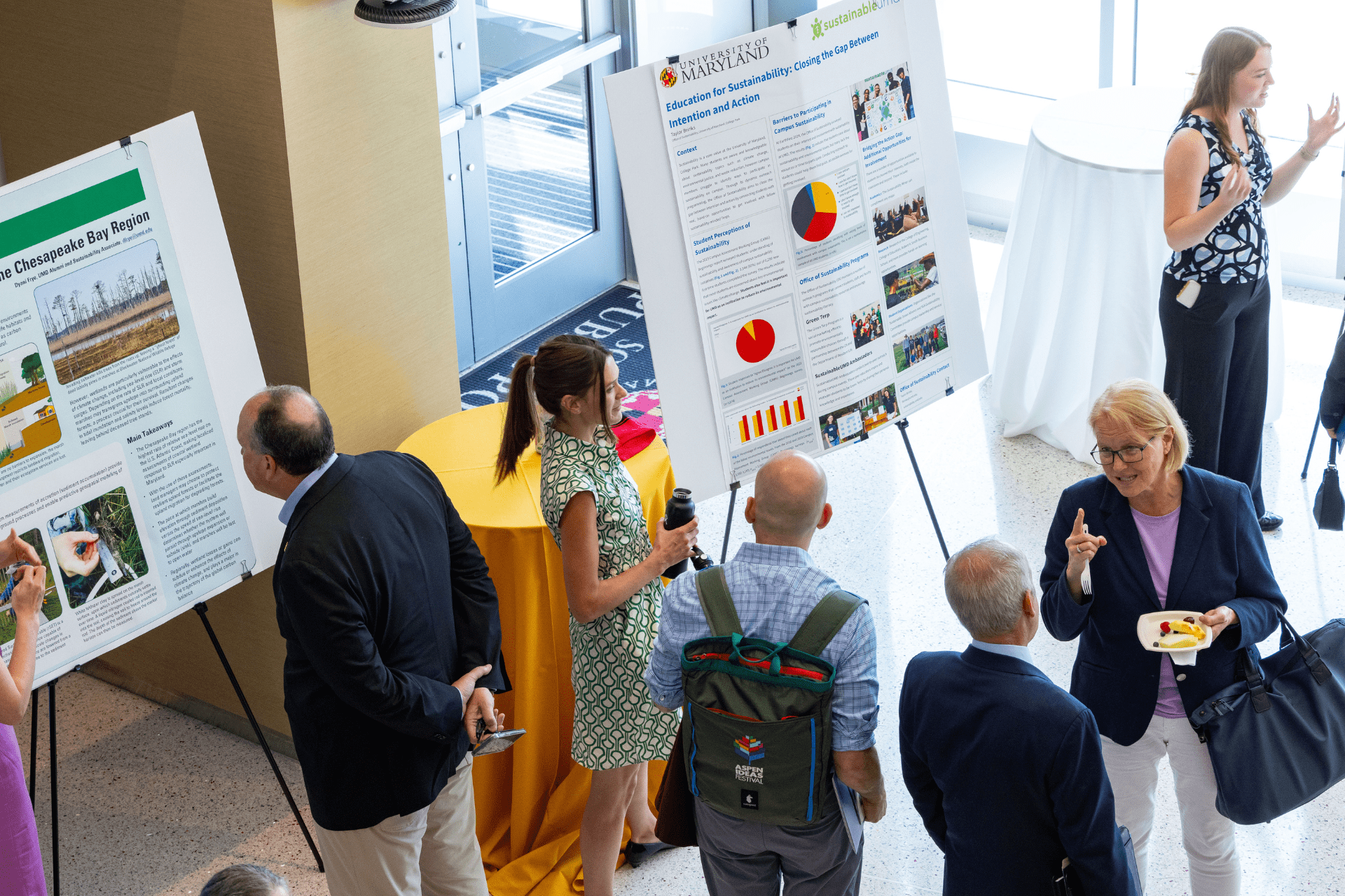 Staff discussing poster with graphs on student interest in sustainability