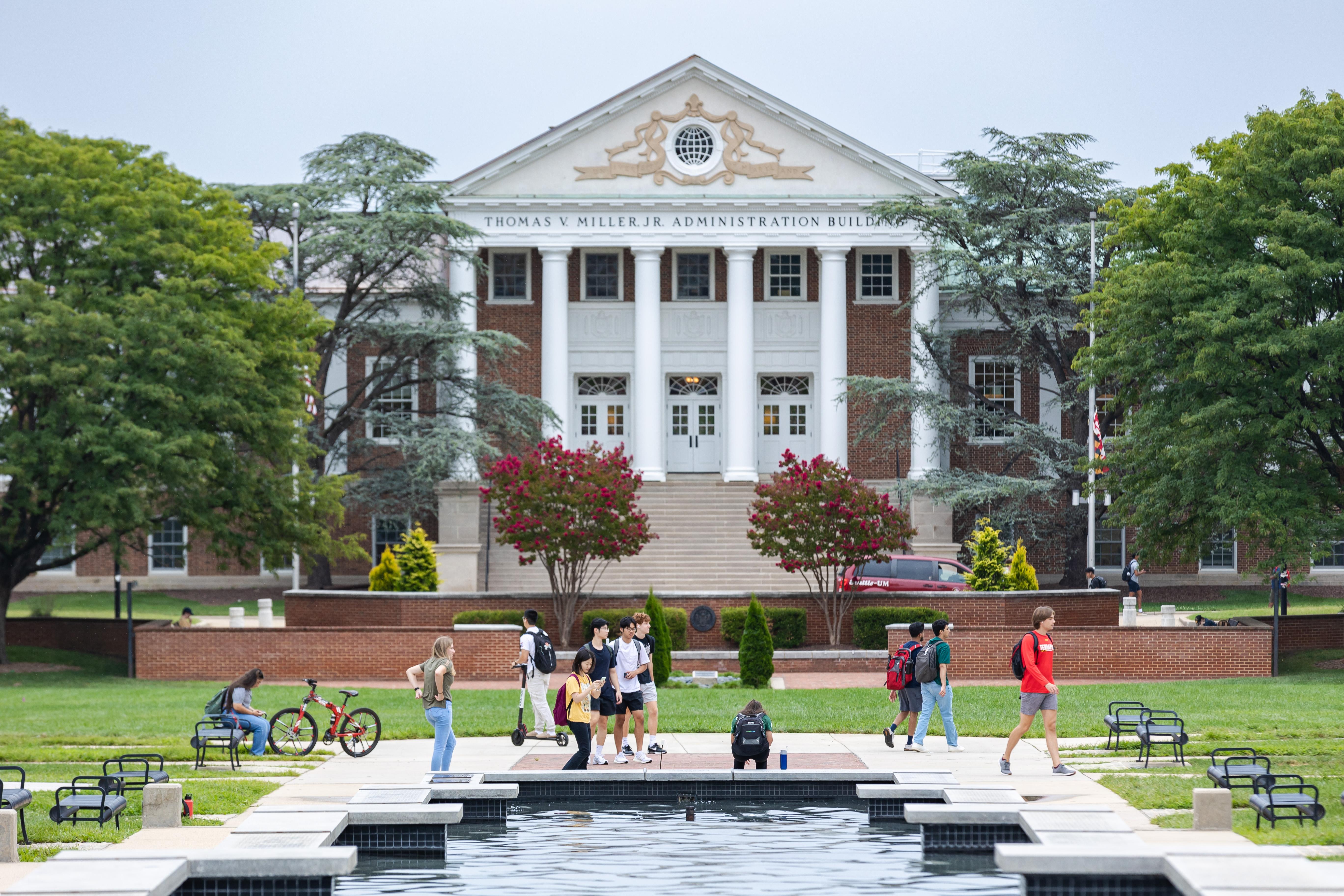 Students walking, biking and scootering in front of the Main Administration Building on McKeldin Mall (2023)