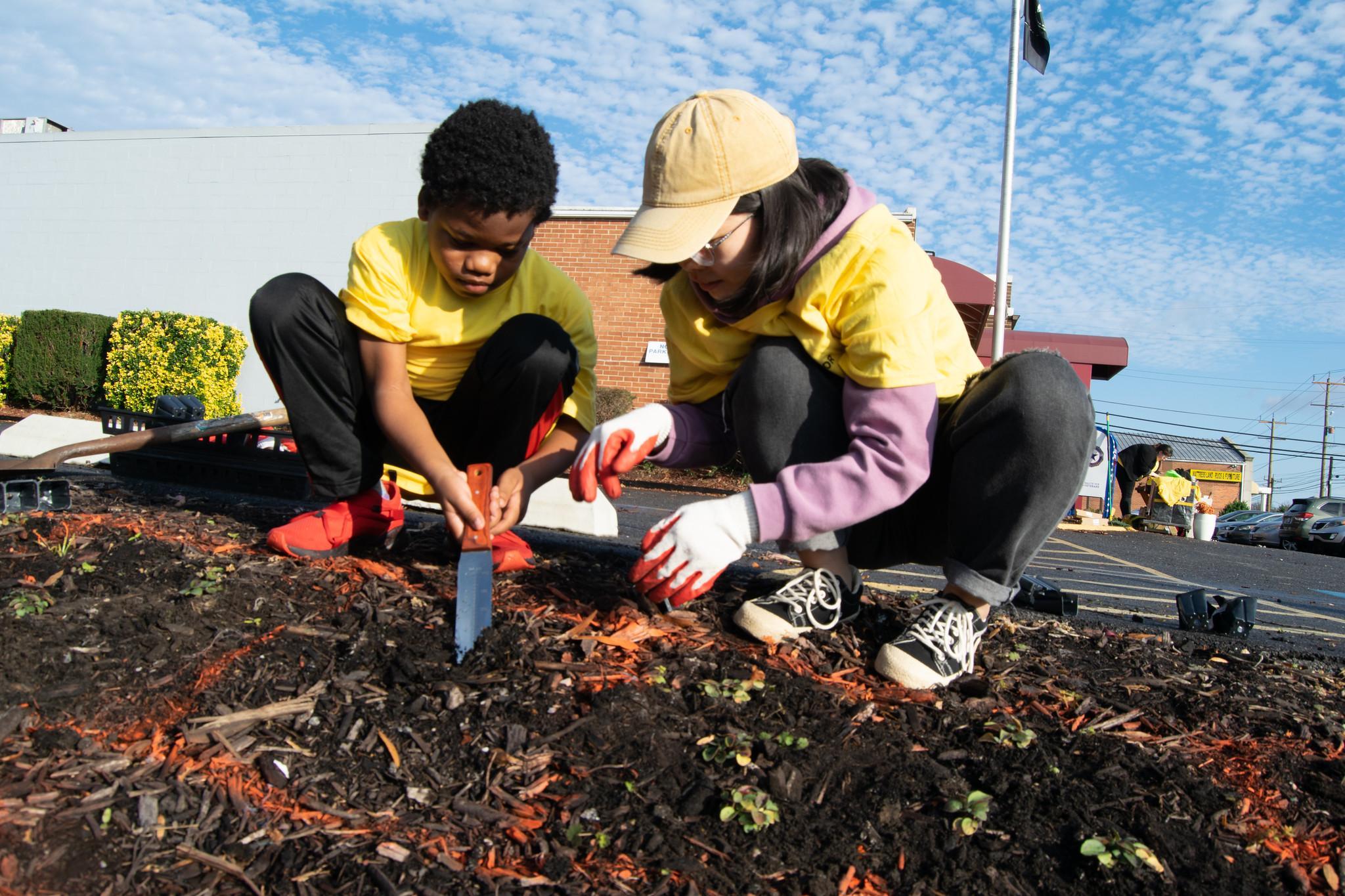 Child and woman working together on planting in a urban parking lot (on Good Neighbor Day 2023)