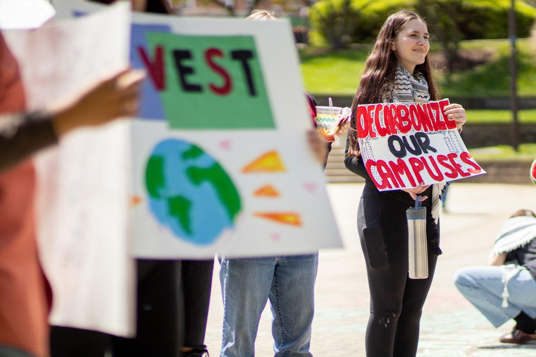 Students stand in Hornbake Plaza holding signs about climate change and decarbonization.