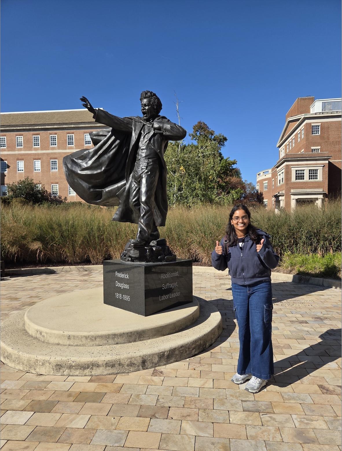 A student poses in front of the UMD Frederick Douglass article.
