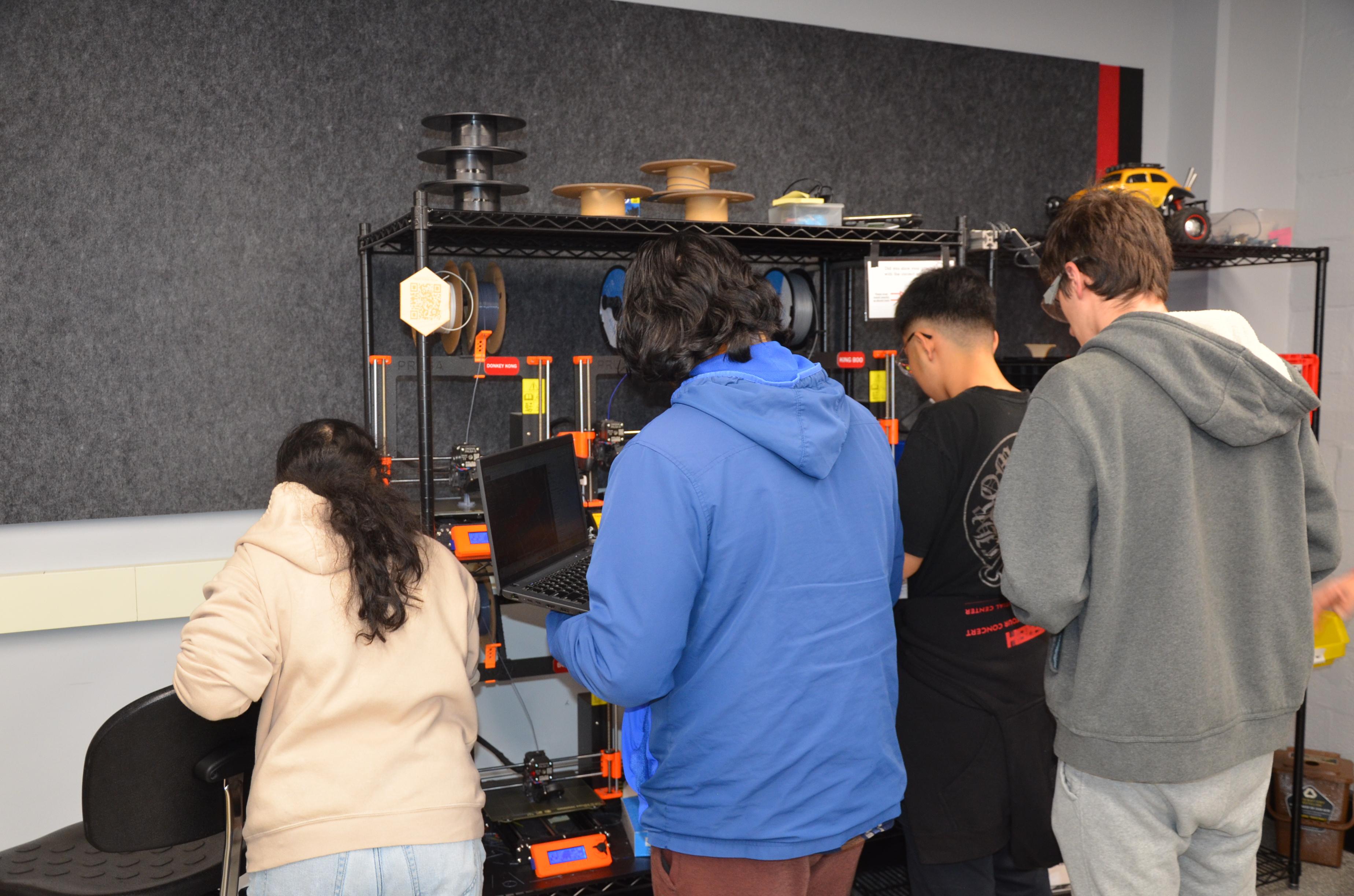 Engineering students huddle around a computer