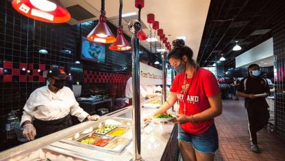 Students selecting food at a campus dining hall counter.