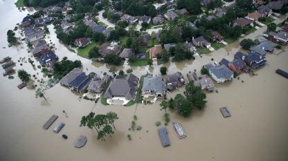Aerial view of a residential neighborhood flooded with muddy water surrounding houses and streets.