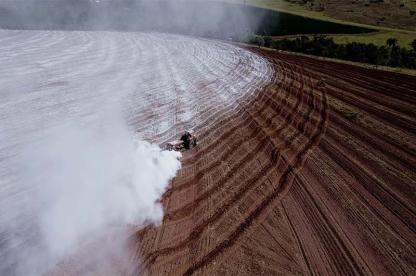 Tractor spreading rock dust across a farm field to improve soil and capture carbon.